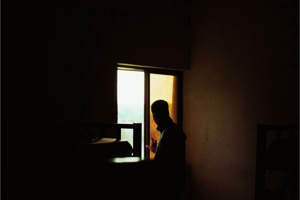 Homem sozinho em uma sala pouco iluminada, transmitindo sensação de vigilância e atenção à segurança doméstica